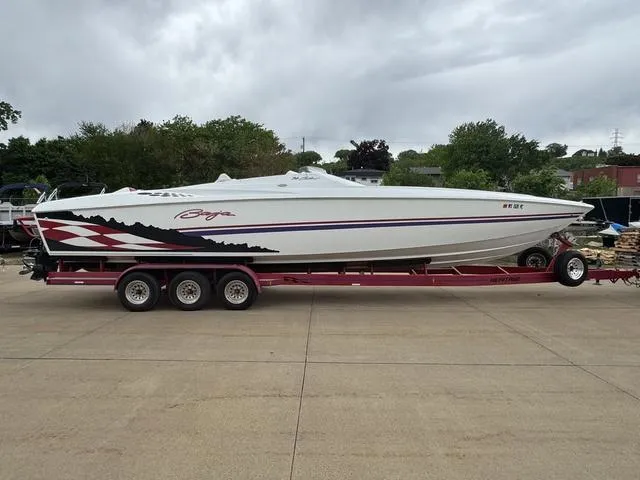 Slide: The Image of 2000 Baja 36 Outlaw speedboat on trailer, white with red and black accents, parked outdoors. - 1