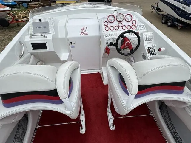 Slide: The Image of 2000 Baja 36 Outlaw boat cockpit with white seats, red accents, and Garmin navigation system. - 11