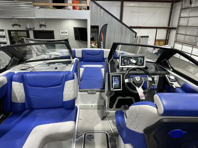 Slide: The Image of 2021 Malibu M220 boat interior with blue and gray seating, modern dashboard, and steering wheel. - 10