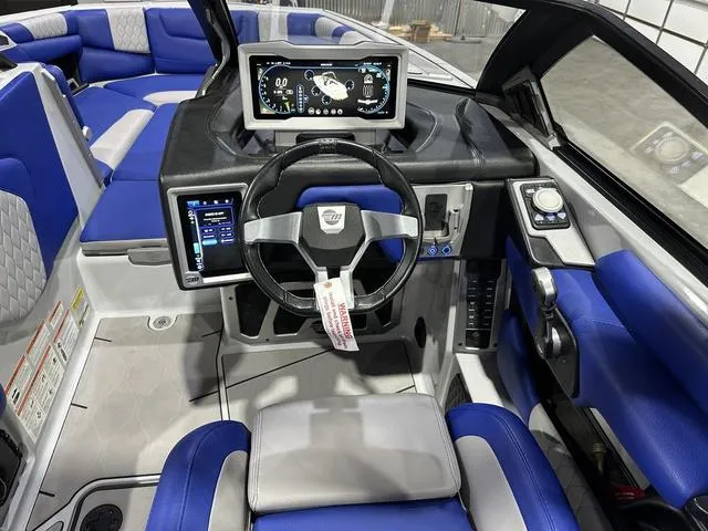Slide: The Image of 2021 Malibu M220 boat interior with modern dashboard, steering wheel, and blue seating. - 11