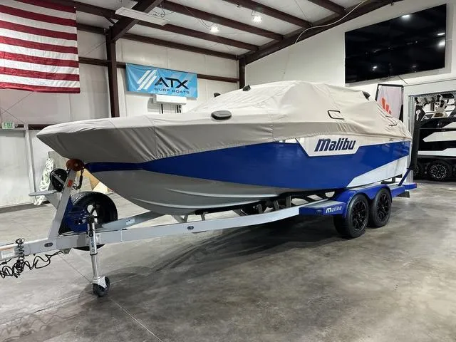 Slide: The Image of 2021 Malibu M220 boat covered on trailer in indoor showroom. - 18