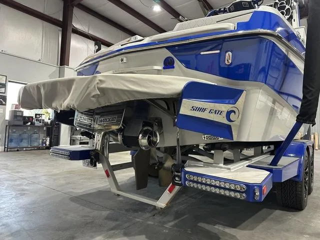 Slide: The Image of 2021 Malibu M220 boat in a garage, showcasing Surf Gate and Power Wedge features. - 3