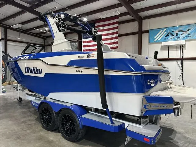 Slide: The Image of 2021 Malibu M220 boat in a garage, blue and white design, on a trailer. - 4