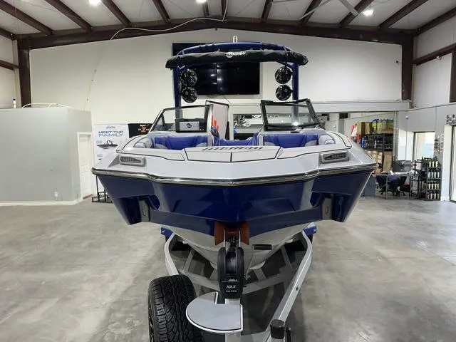 Slide: The Image of 2021 Malibu M220 boat in showroom, front view, blue and white design. - 6