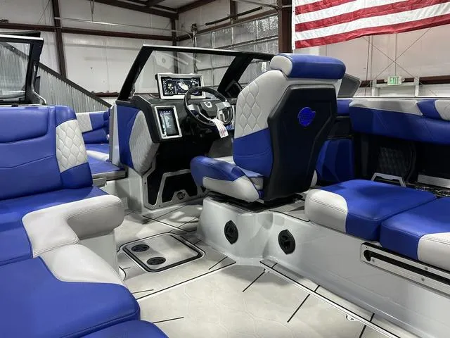 Slide: The Image of Interior of 2021 Malibu M220 boat with blue and gray seating, modern dashboard, and American flag. - 9