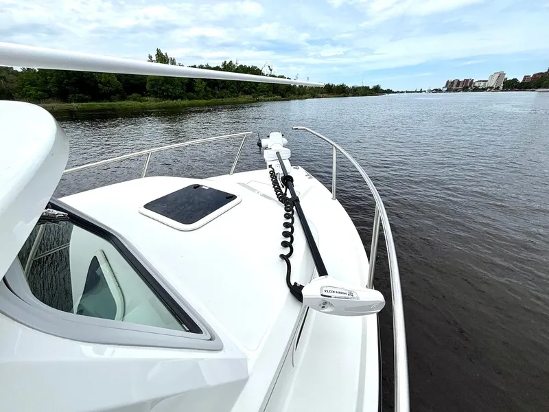 Slide: The Image of 2022 Parker 2320 Sport Cabin boat on calm river with scenic shoreline. - 11