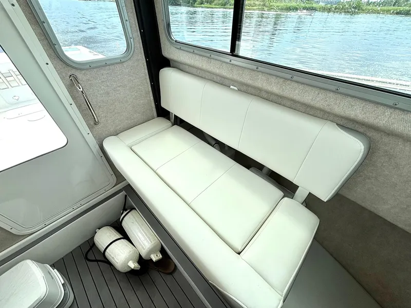 Slide: The Image of 2022 Parker 2320 Sport Cabin interior with white seating and water view. - 14