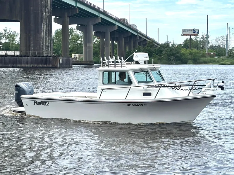 Slide: The Image of 2022 Parker 2320 Sport Cabin boat cruising under a bridge on a river. - 3