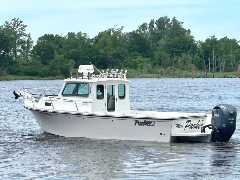 Slide: The Image of 2022 Parker 2320 Sport Cabin boat on a calm lake with wooded shoreline. - 4