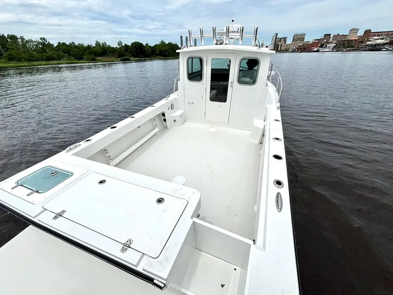 Slide: The Image of 2022 Parker 2320 Sport Cabin boat on calm water, featuring spacious deck and cabin. - 8