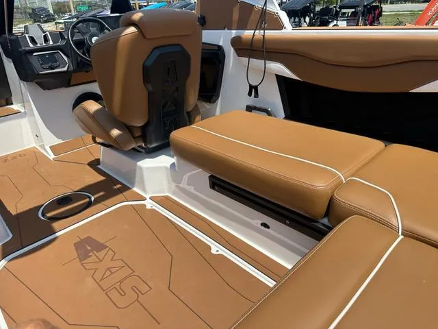 Slide: The Image of 2025 Axis Wake Research T Series T220 boat interior with brown leather seating and modern dashboard. - 10