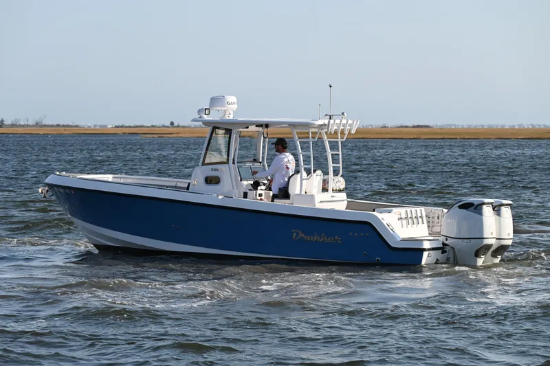 Slide: The Image of 2022 Drakkar 280 CC boat cruising on open water, featuring a sleek blue design. - 2