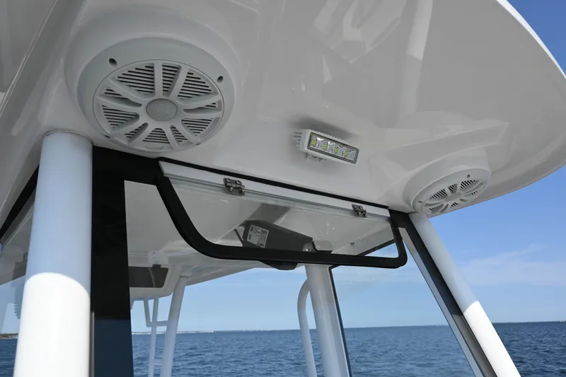 Slide: The Image of 2022 Drakkar 280 CC boat speakers and light under canopy, ocean in background. - 21