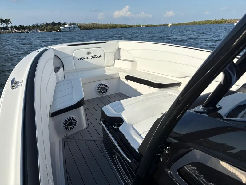 Slide: The Image of 2025 Nor-Tech 340 Sport boat interior with white seating, on a sunny day by the water. - 14