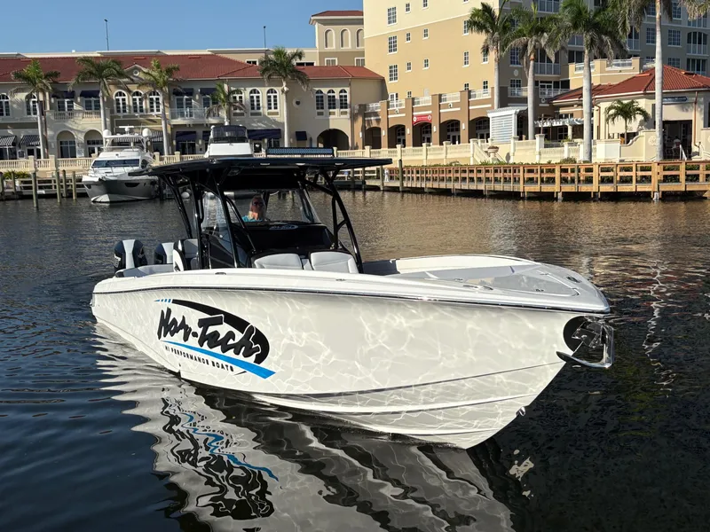 Slide: The Image of 2025 Nor-Tech 340 Sport boat docked in a marina, surrounded by waterfront buildings. - 2