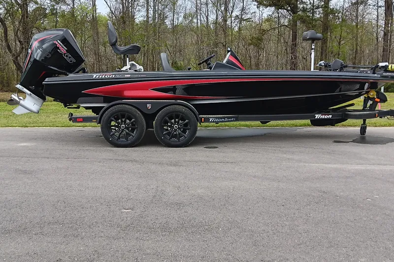 The Image of 2025 Triton 20XP Patriot boat on trailer, black and red design, parked on road. - 0
