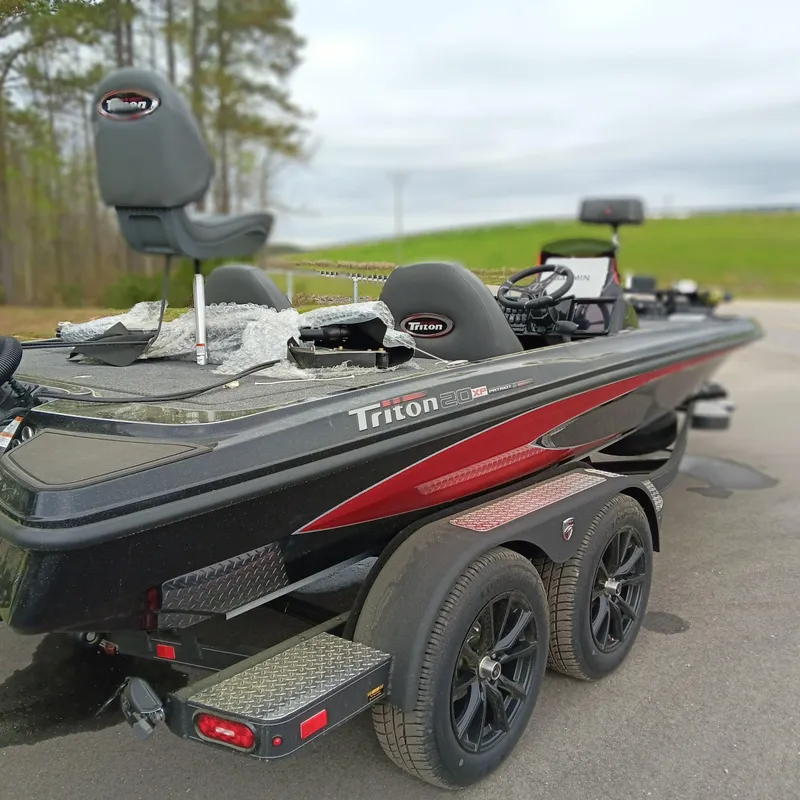 Slide: The Image of 2025 Triton 20XP Patriot boat on trailer, black and red design, parked outdoors. - 3