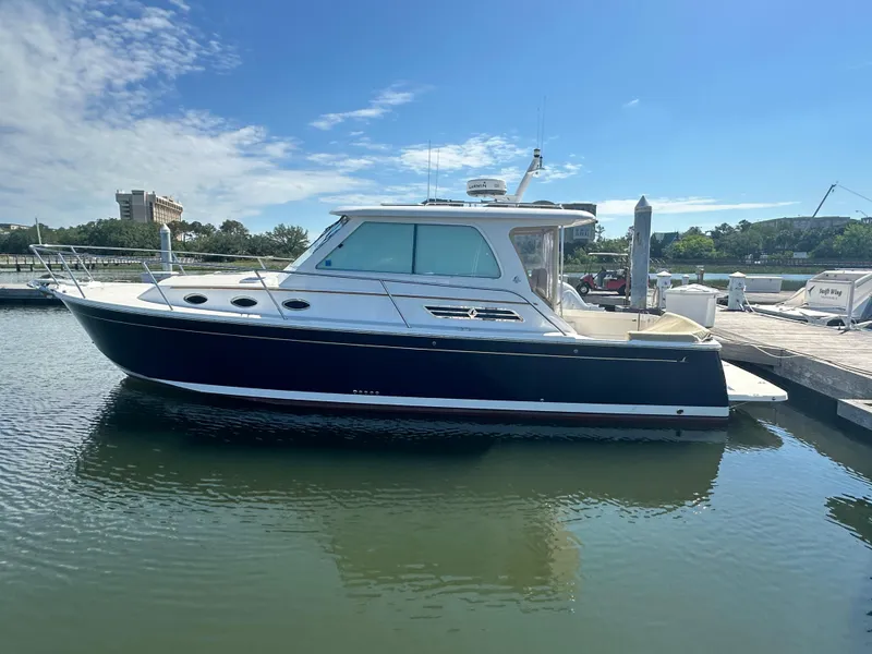 Slide: The Image of 2013 Back Cove 34 boat docked in a marina under a clear blue sky. - 0