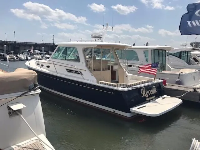 Slide: The Image of 2013 Back Cove 34 yacht docked at marina, featuring sleek design and American flag. - 2