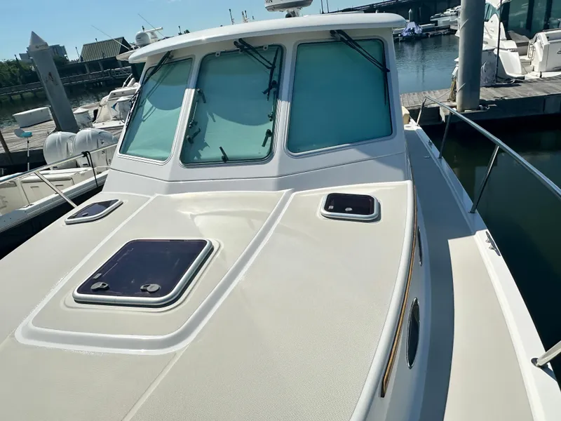 Slide: The Image of 2013 Back Cove 34 boat docked, showcasing cabin windows and deck hatches. - 23