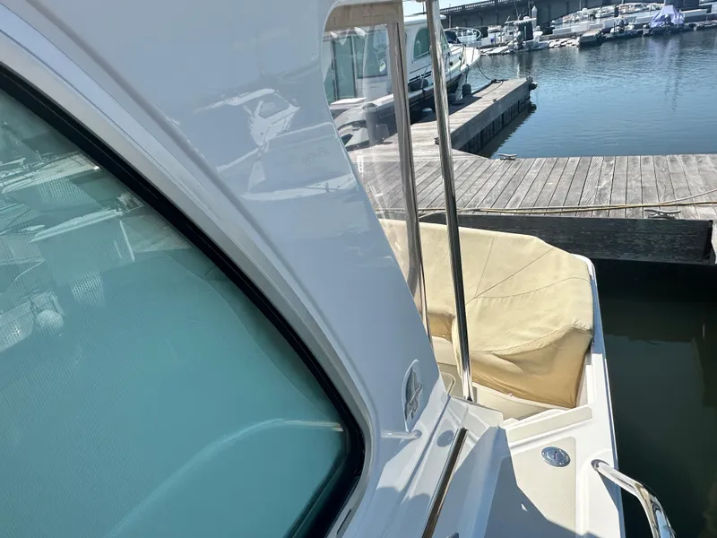 Slide: The Image of 2013 Back Cove 34 yacht docked at marina, featuring sleek design and covered seating area. - 27