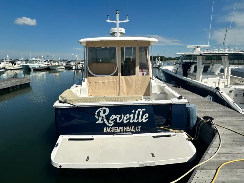 Slide: The Image of 2013 Back Cove 34 boat docked at marina, named "Reveille," with clear blue sky. - 3