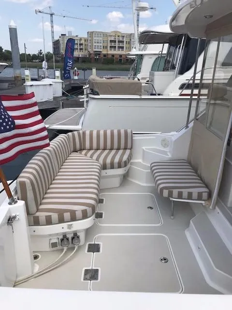 Slide: The Image of 2013 Back Cove 34 yacht with striped seating and American flag at marina. - 31