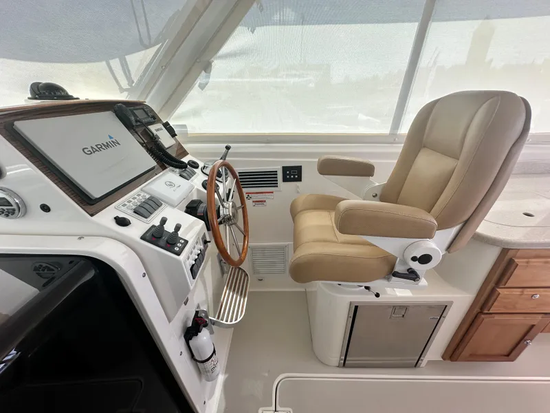 Slide: The Image of 2013 Back Cove 34 helm with Garmin navigation, beige captain's chair, and wooden cabinetry. - 44