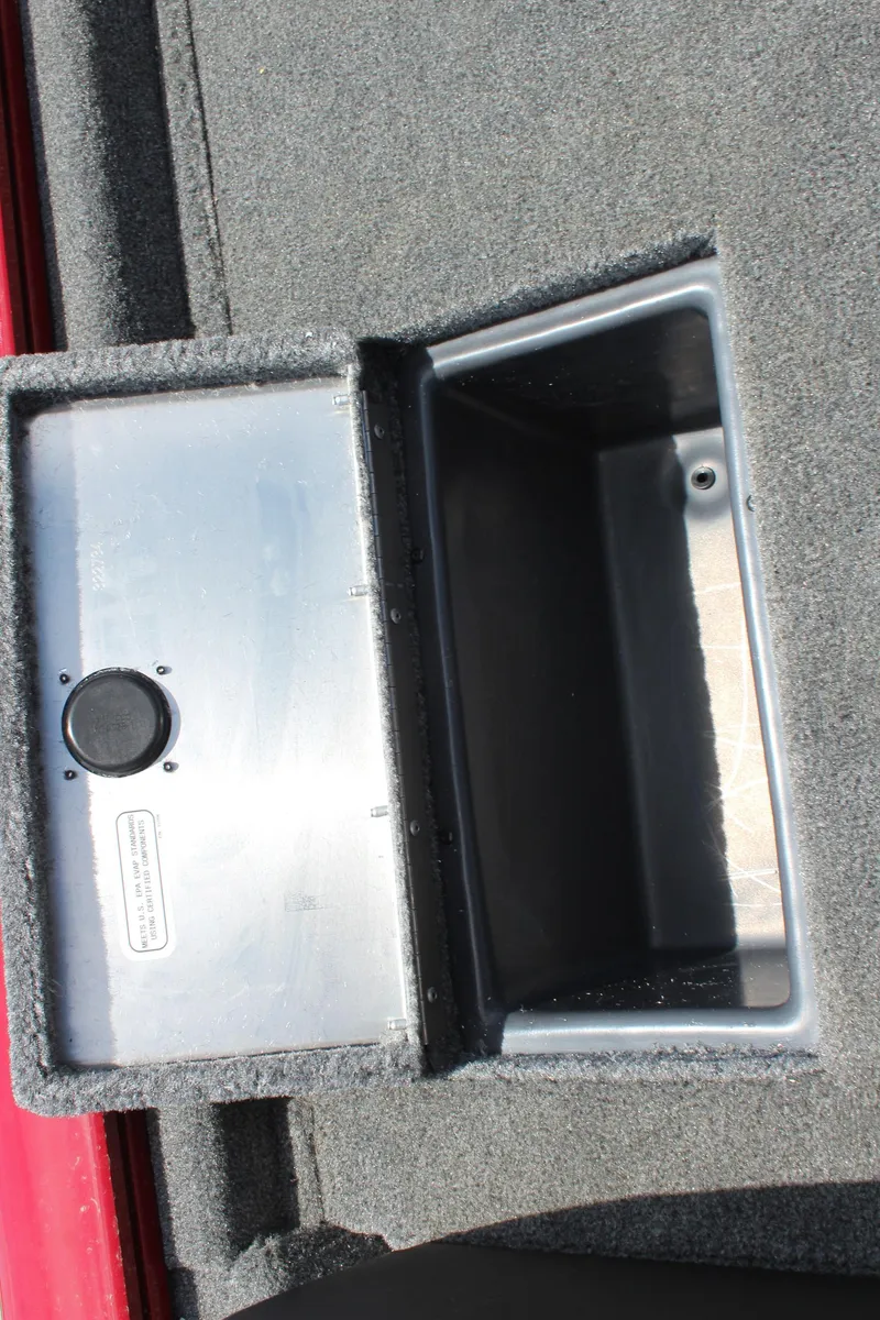 Slide: The Image of 2025 Tracker Pro Team 175 boat storage compartment with gray carpeted interior. - 17