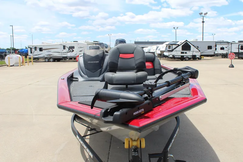 Slide: The Image of 2025 Tracker Pro Team 175 boat, red and black, parked near RVs under a cloudy sky. - 2