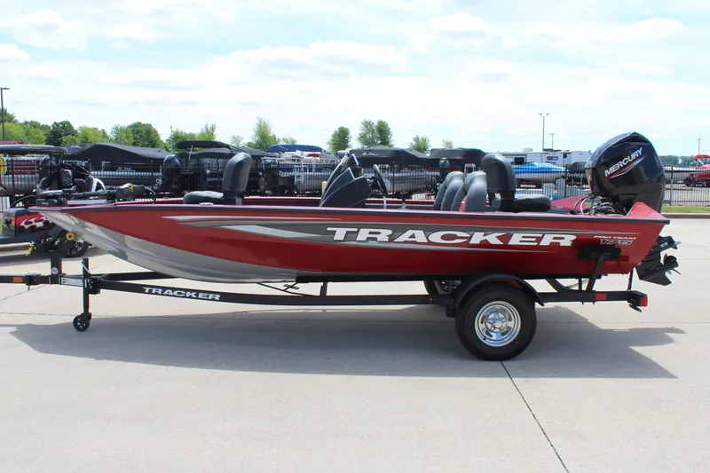 Slide: The Image of 2025 Tracker Pro Team 175 boat, red with silver accents, on a trailer in a parking lot. - 4