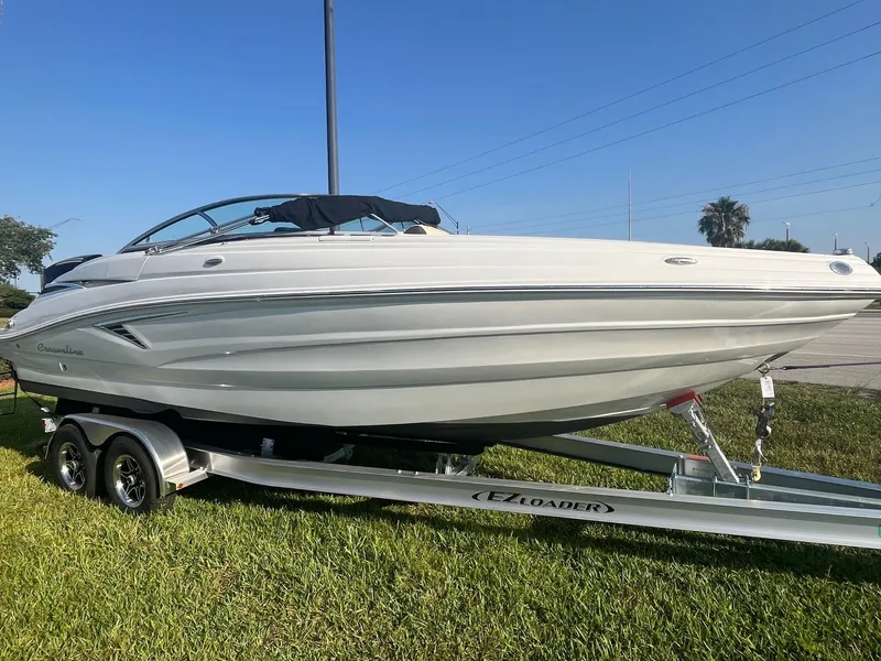 Slide: The Image of 2022 Crownline 260 XSS boat on trailer, parked on grass under clear blue sky. - 1