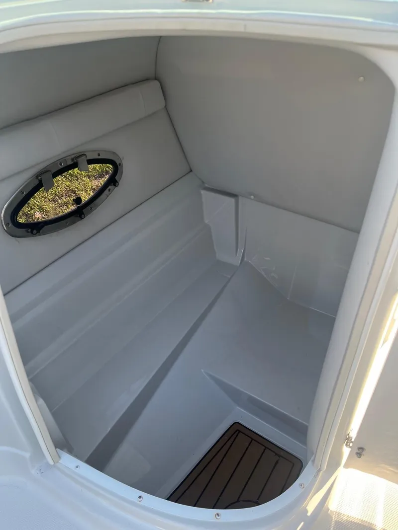 Slide: The Image of 2022 Crownline 260 XSS boat interior cabin with window and wooden floor detail. - 12