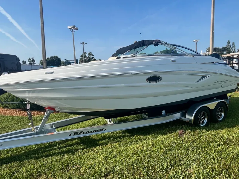Slide: The Image of 2022 Crownline 260 XSS boat on trailer, displayed outdoors on grass. - 2