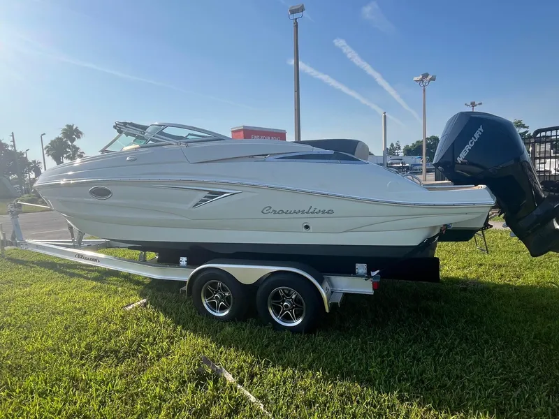 Slide: The Image of 2022 Crownline 260 XSS boat on trailer, parked on grass under clear blue sky. - 3