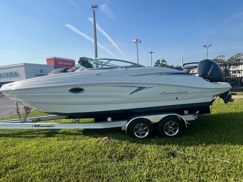 Slide: The Image of 2022 Crownline 260 XSS boat on trailer, parked on grass under clear sky. - 4