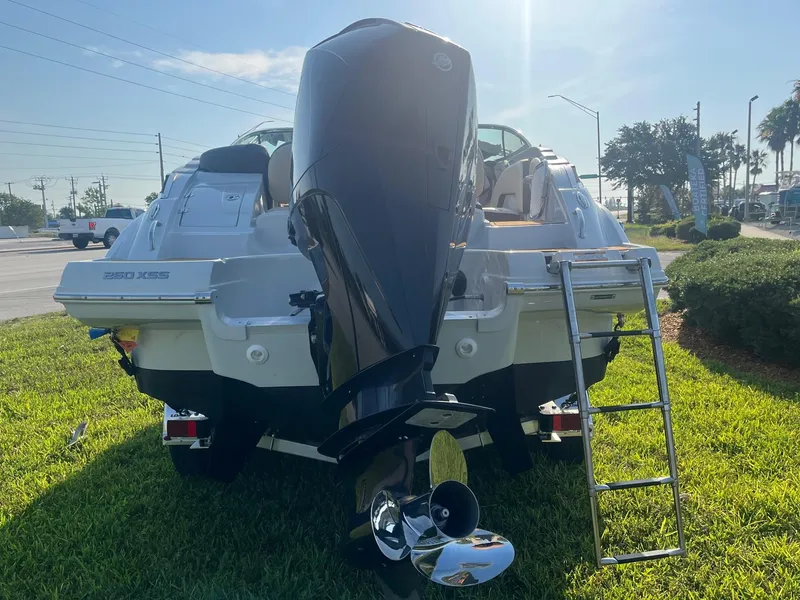 Slide: The Image of 2022 Crownline 260 XSS boat with outboard motor and ladder on grass. - 5
