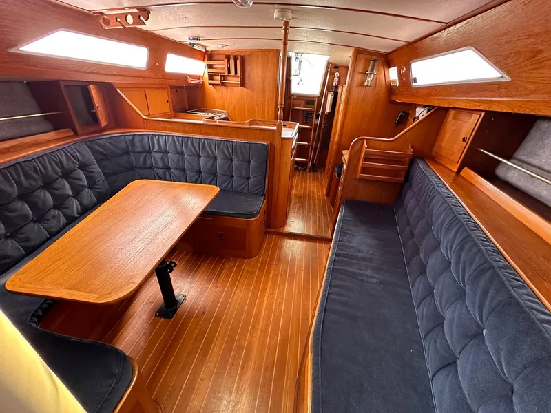 Slide: The Image of 1985 Whiting 40 yacht interior with wooden finish and blue cushioned seating. - 12