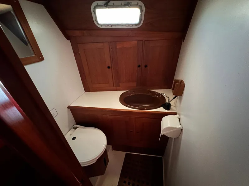 Slide: The Image of Compact wooden boat bathroom with sink, toilet, and storage cabinets, Whiting 40, 1985 model. - 22