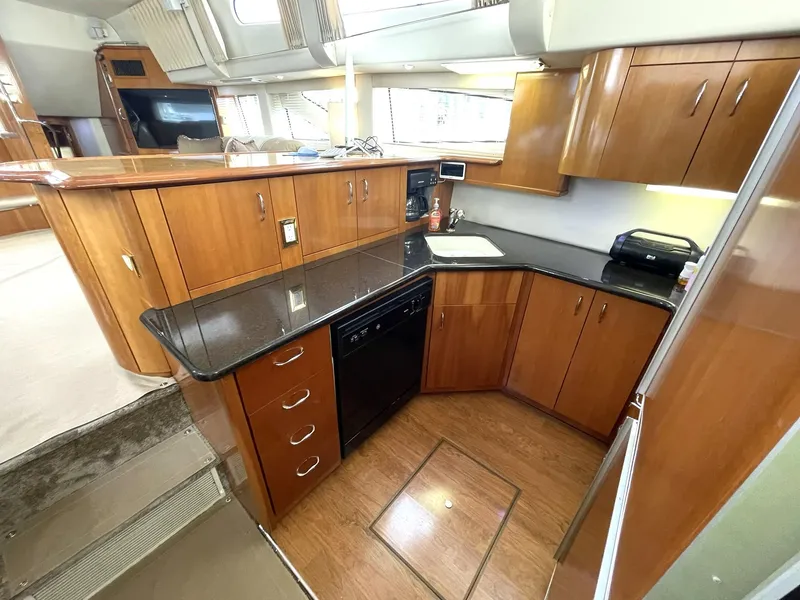 Slide: The Image of 2006 Carver 466 Motor Yacht kitchen with wood cabinets, black countertops, and modern appliances. - 22