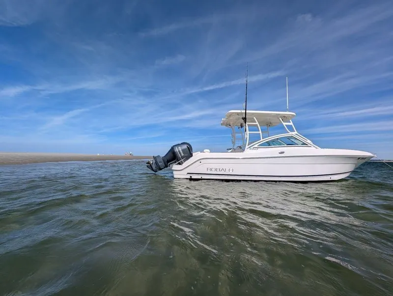 Slide: The Image of 2018 Robalo R247 Dual Console boat on calm water under blue sky. - 2