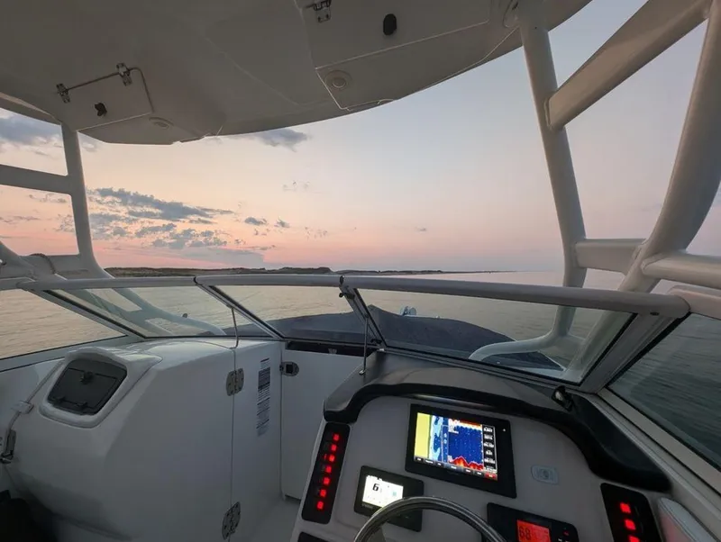 Slide: The Image of 2018 Robalo R247 Dual Console boat interior at sunset, featuring navigation equipment. - 5