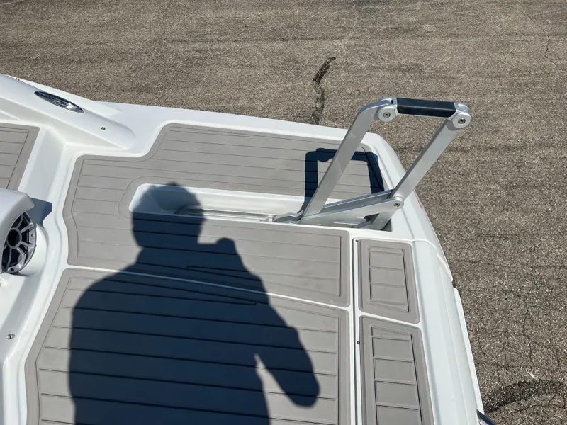 Slide: The Image of 2026 Crownline 298 SS boat deck with ladder and shadow on textured surface. - 11