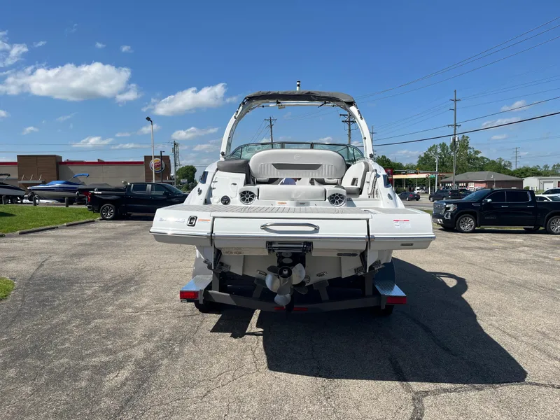 Slide: The Image of 2026 Crownline 298 SS boat, rear view, parked outdoors on a sunny day. - 2