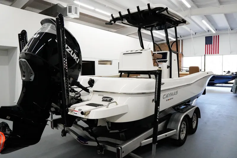 Slide: The Image of 2020 Caymas 26 HB boat with Suzuki engine in a showroom, American flag in background. - 3