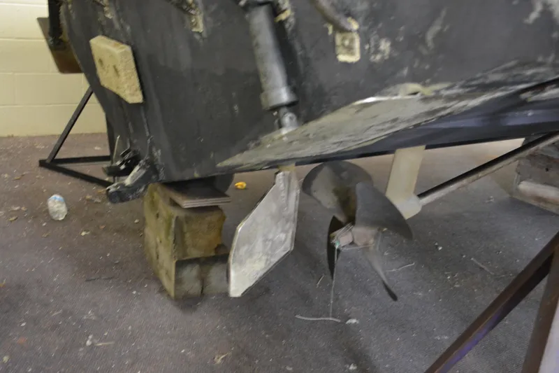 Slide: The Image of 2004 Carolina Classic 28 boat propeller and rudder on blocks in a workshop. - 10