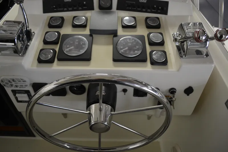 Slide: The Image of 2004 Carolina Classic 28 boat dashboard with steering wheel and control gauges. - 23