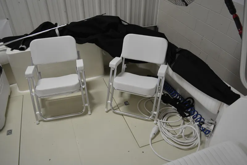 Slide: The Image of 2004 Carolina Classic 28 boat interior with two white chairs and coiled ropes. - 28