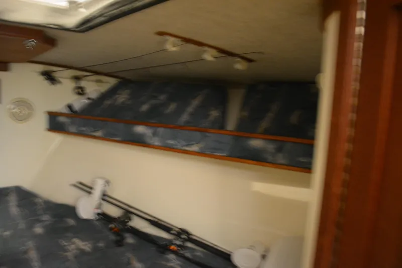 Slide: The Image of 2004 Carolina Classic 28 cabin interior with fishing rods and blue patterned seating. - 30