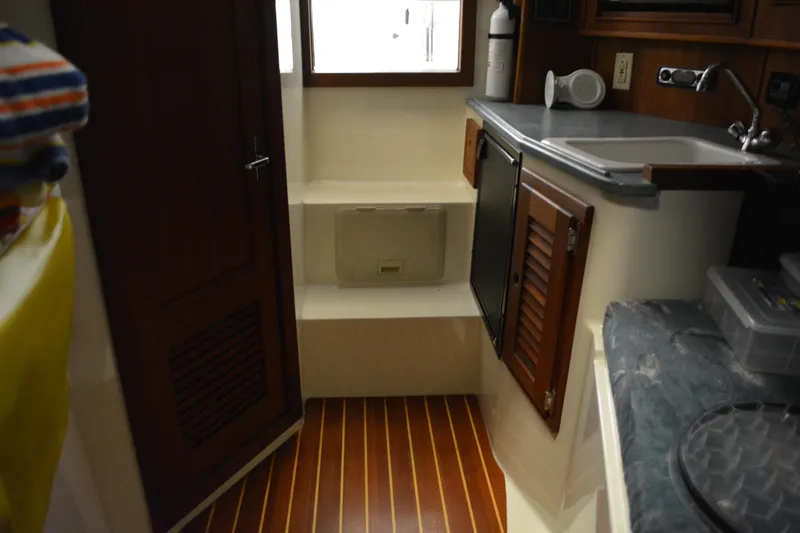 Slide: The Image of Interior of 2004 Carolina Classic 28 boat with wood flooring and compact kitchenette. - 37